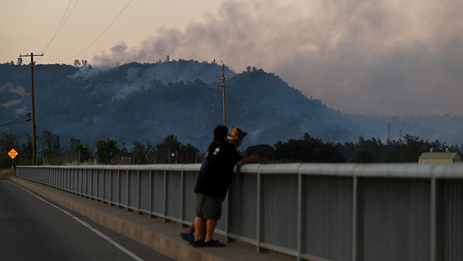 Men watch the Thompson Fire as wildfires continue in Oroville of Butte County in California, on July 2, 2024.