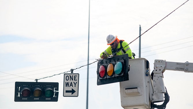 A linesman repairs a stoplight in Houston, Texas on July 11, 2024. Millions of people in Texas are still grappling with power outages and facing the looming dangers of intense heat and humidity following Hurricane Beryl.