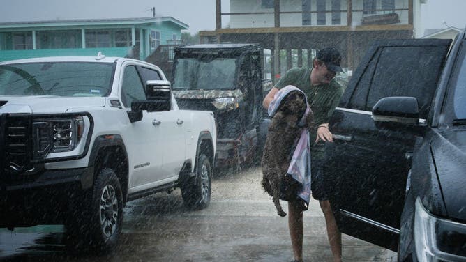 Black Braun loads his dog Dolly into his family's vehicle as outer bands from Tropical Storm Beryl begin to hit the coast Sunday, July 7, 2024, in Port O'Connor.