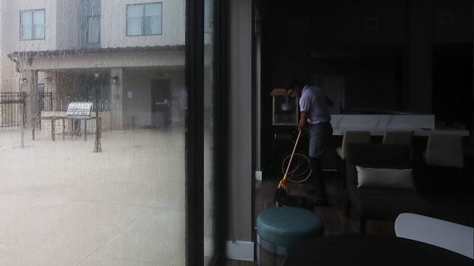 Andrew Parada, an employee at Residence Inn, mops up the floor as water leaks during Hurricane Beryl on Monday, July 8, 2024, in Galveston.