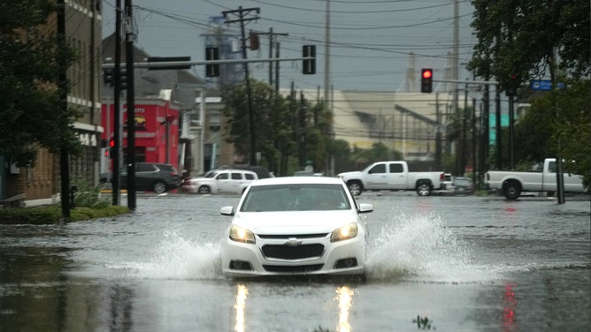 A sedan makes it way down a flooded street near downtown Galveston as Hurricane Beryl wanes on Monday, July 8, 2024.