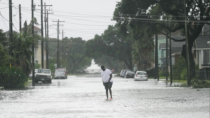 A man walks down the middle of a flooded road in Galveston on Monday, July 8, 2024, as Hurricane Beryl wanes.