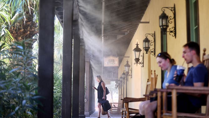 People gather beneath misters at a hotel during a long-duration heat wave which is continuing to impact much of California on July 10, 2024 in Death Valley National Park, California