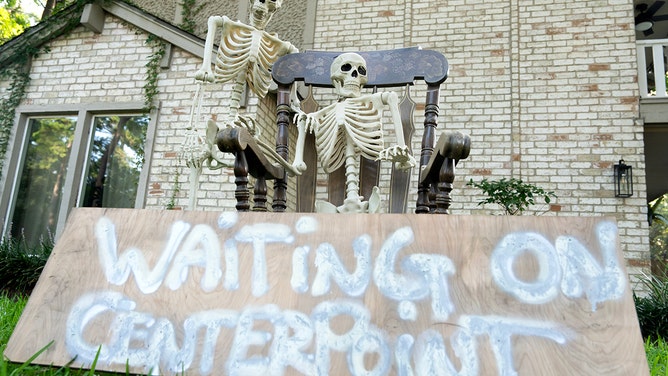 A pair of skeletons along with a sign that reads 'Waiting on CenterPoint' is seen on the front yard of Rex Mackall Jr.s home as his family and neighborhood still remain without power four days after Hurricane Beryl made landfall, Thursday, July 11, 2024, in Spring.