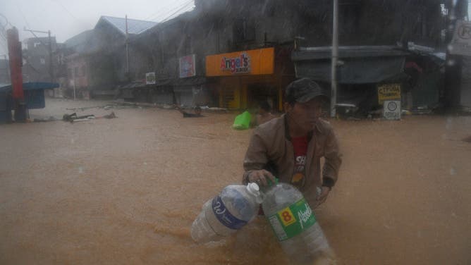 A resident wades through floodwaters in Manila on July 24, 2024, amid heavy rains brought by Typhoon Gaemi.