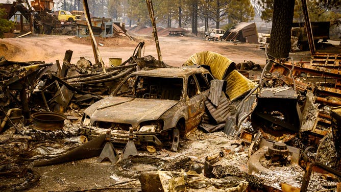 A burned vehicle smolders in the Paynes Creek area of unincorporated Tehama County, California, during the Park fire on July 27, 2024. The fast-moving and rapidly growing wildfire has forced more than 4,000 people to evacuate as firefighters battle gusty winds and perilously dry conditions, authorities said on July 26, 2024. An arsonist is suspected to have started the fire which has burned more than 340,000 acres and burned dozens of homes. (Photo by JOSH EDELSON / AFP) (Photo by JOSH EDELSON/AFP via Getty Images)