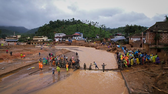 An aerial view shows people crossing a temporary bridge at the site of a landslide on July 31, 2024 in Chooralmala village, India.