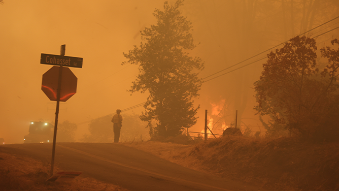 A firefighter is seen standing near the flames from the massive Park Fire burning near Chico in Northern California.