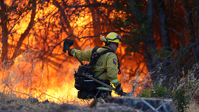 A firefighter is seen standing near the flames from the massive Park Fire burning near Chico in Northern California.