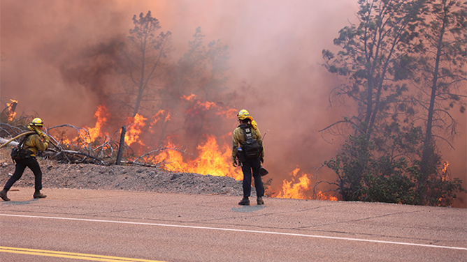 A firefighter is seen standing near the flames from the massive Park Fire burning near Chico in Northern California.