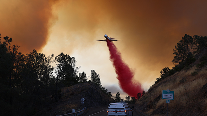 An airplane is seen dropping fire retardant on the Park Fire burning outside Chico, California.