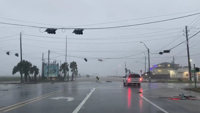 Winds pull down a traffic light in Surfside Beach, Texas during Hurricane Beryl's storm surge on July 8, 2024.