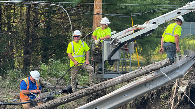 Utility crews are seen next to downed power lines and downed utility pole in Lyndonvolle, Vermont, after catastrophic flooding on Tuesday, July 30, 2024.