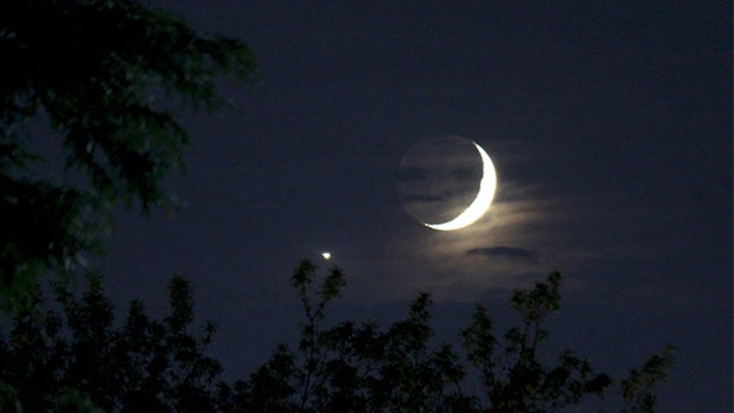 A waxing crescent moon setting in the early evening with bright Venus visible nearby. 