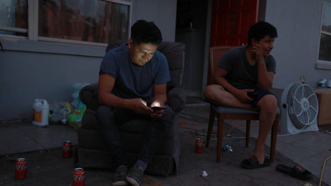 FILE - Esteban Hernandez looks at his cell phone as he sits outside his house that has no electricity on October 07, 2022 in Fort Myers, Florida. Many homes continue to lack water and electricity over a week after Hurricane Ian brought high winds, storm surges, and rain to the area, causing severe damage. (Photo by Joe Raedle/Getty Images)