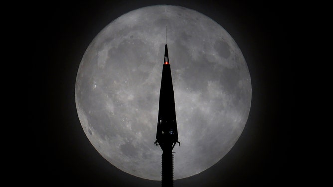 The Blue Supermoon rises behind the antenna on top of One World Trade Center in New York City on August 30, 2023, as seen from Jersey City, New Jersey.