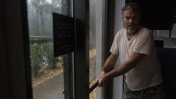 A visitor keeps a hotel door from swinging open as Hurricane Debby makes landfall in Perry, Florida, on Monday.