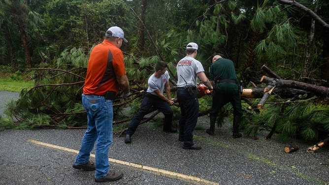 Members of local law enforcement and fire rescue crews clear fallen trees from the road as Hurricane Debby makes landfall in Steinhatchee, Florida, US, on Monday, Aug. 5, 2024.