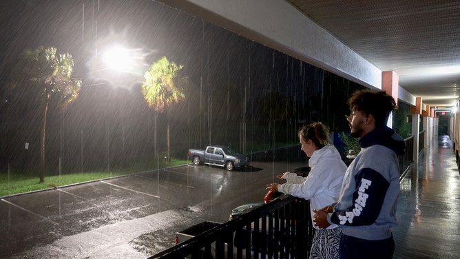Anna Davis and her son Paul Davis look out from the balcony of a hotel at the wind and rain kicked up by Hurricane Debby on Monday in Chiefland, Florida.