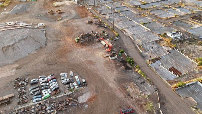 An aerial view of destroyed and damaged cars (L) next to lots which have been cleared of wildfire debris, covered in gray gravel, on August 4, 2024 in Lahaina, Hawaii.