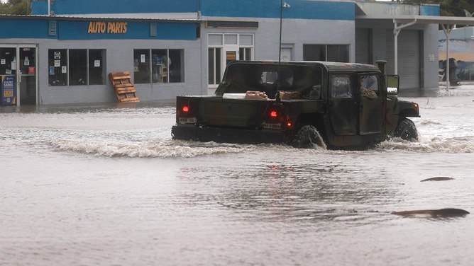 A Florida National Guard vehicle drives through a flooded street caused by the rain and storm surge from Hurricane Debby on August 05, 2024, in Cedar Key, Florida.