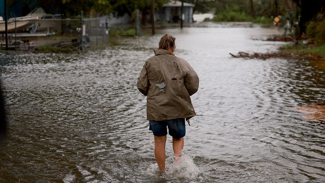 A person walks through a flooded street caused by the rain and storm surge from Hurricane Debby on August 05, 2024, in Cedar Key, Florida.