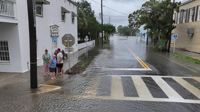 In an aerial view, people look out onto a flooded street caused by the rain and storm surge from Hurricane Debby on August 05, 2024, in Cedar Key, Florida.