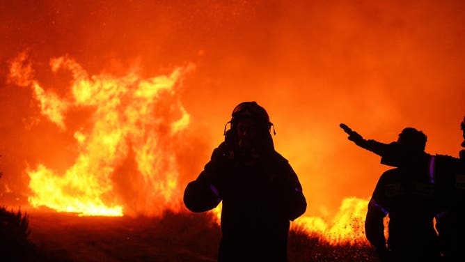 Firefighters attempt to control a wildfire in Dionysos, Greece, on Monday, Aug. 12, 2024. A huge wildfire is threatening suburbs on the outskirts of Athens, forcing thousands of people to evacuate as houses were set alight and local hospitals put at risk. Photographer: Nick Paleologos/Bloomberg via Getty Images