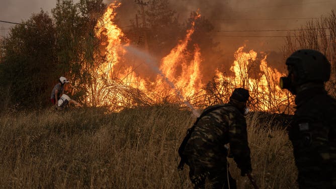 Volunteers try to extinguish a wildfire near Penteli, on August 12, 2024. Greece's civil protection authorities ordered the evacuation of several towns in the north-eastern suburbs of Athens, threatened by a violent fire that started the day before and is spreading. European Union said that four countries -- Italy, France, the Czech Republic and Romania -- would send assistance at the request of Greece which is combating a massive wildfire burning through Athens suburbs. (Photo by Angelos TZORTZINIS / AFP) (Photo by ANGELOS TZORTZINIS/AFP via Getty Images)