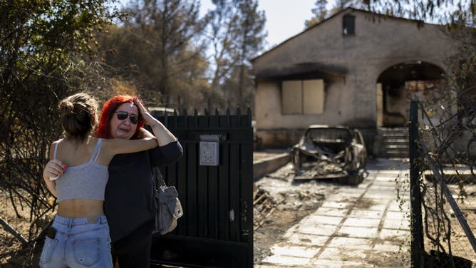 dpatop - 13 August 2024, Greece, Athen: A woman is comforted by a girl in front of her burnt-down house, which was destroyed by a forest fire in Ano Patima near Penteli in the north of Athens. Just a few kilometers northeast of the Greek capital, firefighters are battling countless fires over an area of around 200 square kilometers. The government has now asked the EU for support. Photo: Socrates Baltagiannis/dpa (Photo by Socrates Baltagiannis/picture alliance via Getty Images)