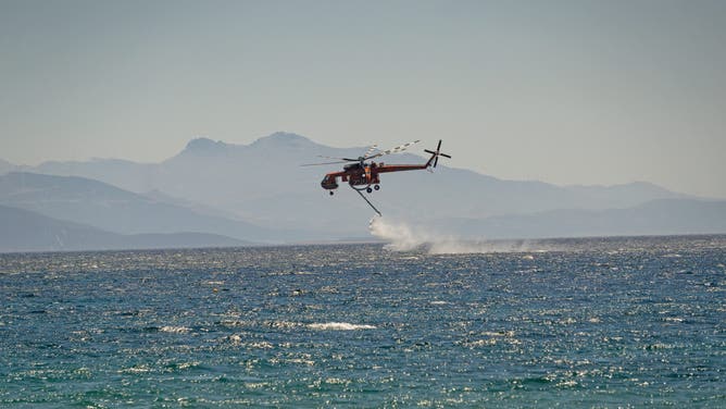 A firefighting helicopter collects water from the sea during wildfire control operations at Nea Makri, east of Athens, Greece, on Tuesday, Aug. 13, 2024. Climate change is turbo-charging the threat posed by wildfires, with Greece suffering its worst season in two decades. Photographer: Ioana Epure/Bloomberg via Getty Images