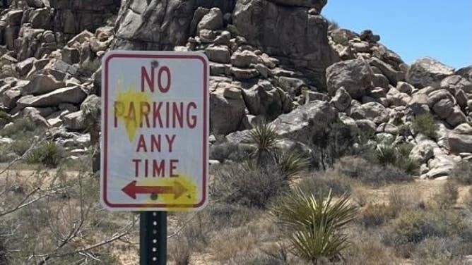 A sign defaced with yellow paintball paint in Joshua Tree National Park.