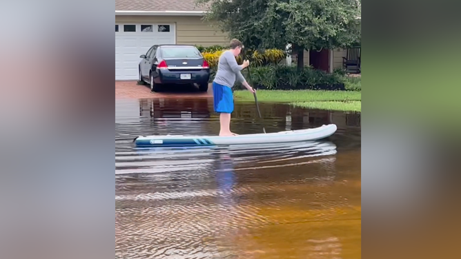 Dr. Martin on a paddleboard, paddling through floodwater caused by Debby.