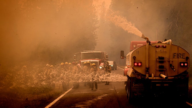 A fire truck sprays water on a spot fire to assist firefighters on State Road 172 during the Park fire in Tehama County's Mill Creek area of California August 7, 2024.