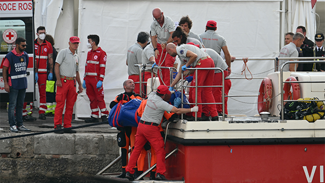 Rescuers carry a body after divers return in Porticello harbor near Palermo, on August 22, 2024, three days after the British-flagged luxury yacht Bayesian sank. Divers searching for six missing people following the sinking of a superyacht off Sicily in a storm have found fifth bodies. The Bayesian, which had 22 people aboard including 10 crew, was anchored some 700 metres from port before dawn when it was struck by a waterspout. Among the six missing were UK tech entrepreneur Mike Lynch and his 18-year-old daughter Hannah, and Jonathan Bloomer, the chair of Morgan Stanley International, and his wife Judy. (Photo by Alberto PIZZOLI / AFP) (Photo by ALBERTO PIZZOLI/AFP via Getty Images)