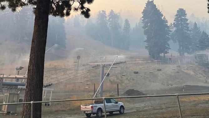 Snowmaking machines spraying water.