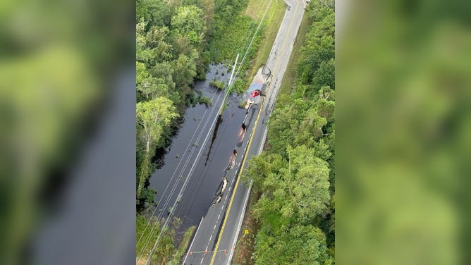 Collapsed portion of Old Ocean Highway in Brunswick County. A red vehicle can be seen stuck in the collapsed road.