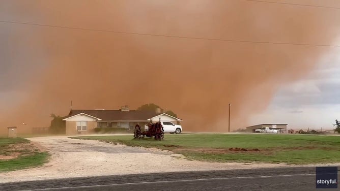 Dust devil blows through field behind house in Anson, Texas.