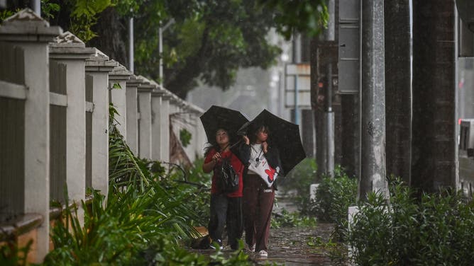 Pedestrians hold their umbrellas amid heavy rains brought by Tropical Storm Yagi in Manila on September 2, 2024. A tropical storm dumped heavy rain in the Philippines for a second day on September 2, causing floods and landslides that have left at least four people dead, including a nine-month-old girl, officials said. (Photo by JAM STA ROSA / AFP) (Photo by JAM STA ROSA/AFP via Getty Images)