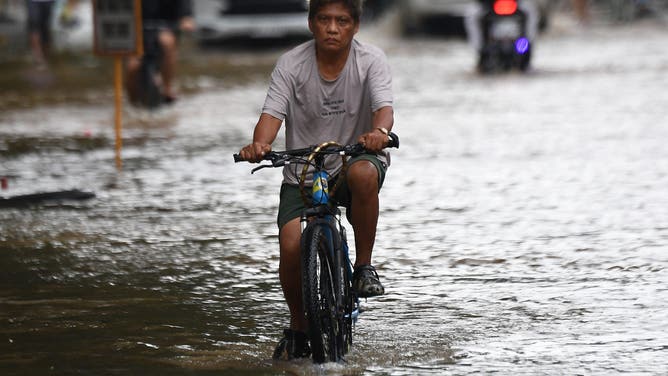 A resident cycles through a flooded street following heavy rains brought about by Tropical Storm Yagi at a village in Cainta town, Rizal province, East of Manila on September 3, 2024. Floods and landslides killed 11 people after a fierce tropical storm dumped heavy rain on the Philippines for a second day, officials said September 2. (Photo by Ted ALJIBE / AFP) (Photo by TED ALJIBE/AFP via Getty Images)