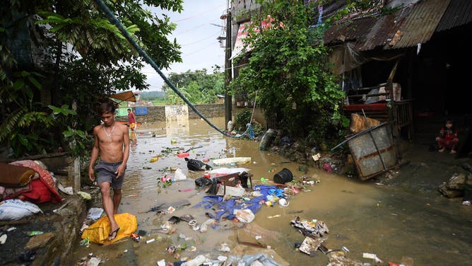 A resident walks past debris of trash swept by flood waters following heavy rains brought about by Tropical Storm Yagi at a village in Cainta town, Rizal province, East of Manila on September 3, 2024. Floods and landslides killed 11 people after a fierce tropical storm dumped heavy rain on the Philippines for a second day, officials said September 2. (Photo by Ted ALJIBE / AFP) (Photo by TED ALJIBE/AFP via Getty Images)