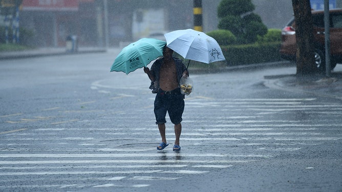 A resident struggles to move forward amid strong wind and heavy rain as Typhoon Yagi makes landfall on September 6, 2024 in Qionghai, Hainan Province of China.