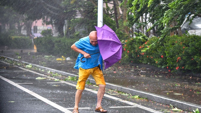A resident struggles to move forward amid strong wind and heavy rain as Typhoon Yagi makes landfall on September 6, 2024 in Wenchang, Hainan Province of China.