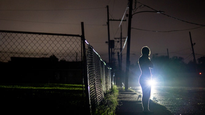 A member of the Brown family stands on a corner waiting for police after their power outage in the Polk Street neighborhood of Houma, Louisiana on September 11, 2024.