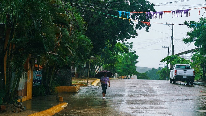 A woman walks under the rain after the passage of hurricane John in Acapulco, Mexico on September 24, 2024.