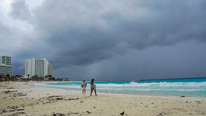 Storm clouds are seen as people walk on the beach ahead of the arrival of Hurricane Helene in Cancun, Quintana Roo, Mexico, on September 24, 2024.