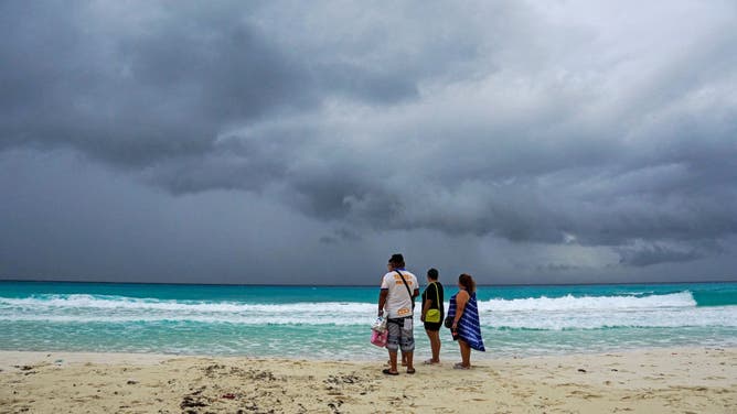 Storm clouds are seen as people walk on the beach ahead of the arrival of Hurricane Helene in Cancun, Quintana Roo, Mexico, on September 24, 2024.