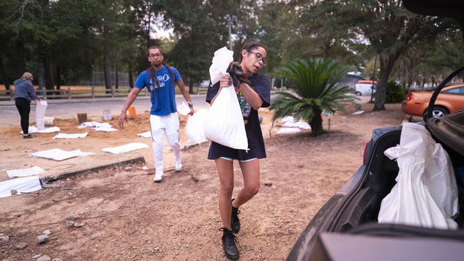 TALLAHASSEE, FLORIDA - SEPTEMBER 25: Kyley Weems, right, and Jordan Rochester carry bags of sand in preparation for possible flooding on September 25, 2024 in Tallahassee, Florida. Forecasts predict that Tropical Storm Helene will strengthen into a hurricane and make landfall along Florida's Gulf Coast on Thursday. (Photo by Sean Rayford/Getty Images)