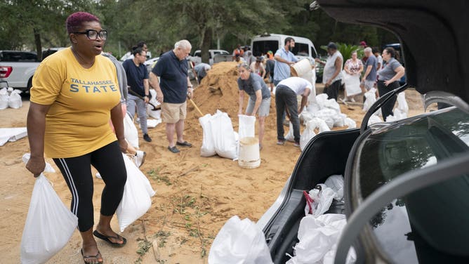 TALLAHASSEE, FLORIDA - SEPTEMBER 25: Tallahassee State professor Pamela Andrews carriers sand bags to a car in preparation for possible flooding as Tropical Storm Helene heads toward the state's Gulf Coast on September 25, 2024 in Tallahassee, Florida. Currently, Tropical Storm Helene is forecast to become a major hurricane, bringing the potential for deadly storm surges, flooding rain, and destructive hurricane-force winds along parts of the Florida West Coast. Helene is expected to make landfall in Florida on Thursday. (Photo by Sean Rayford/Getty Images)