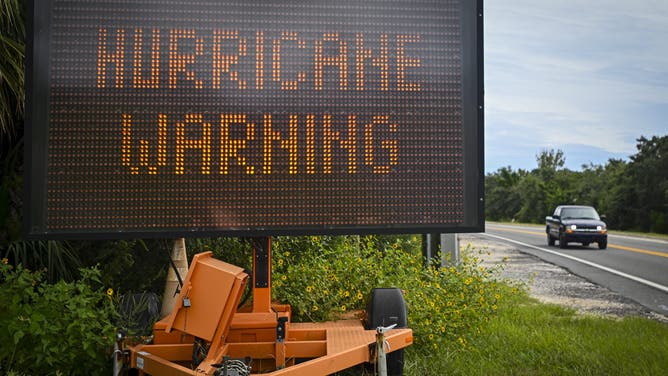 A sign displays a hurricane warning along a roadside as preparations are made for the arrival of Hurricane Helene, in Cedar Key, Florida on September 25, 2024. Thousands of residents on Wednesday began evacuating parts of coastal Florida as the US state braces for Hurricane Helene, forecast to barrel ashore as a powerful, potentially deadly storm. Helene strengthened into a hurricane mid-morning in the Gulf of Mexico and is "expected to bring life-threatening storm surge, damaging winds, and flooding rains to a large portion of Florida and the Southeastern United States," the National Hurricane Center in Miami said in its latest bulletin. (Photo by Miguel J. Rodriguez Carrillo / AFP) (Photo by MIGUEL J. RODRIGUEZ CARRILLO/AFP via Getty Images)